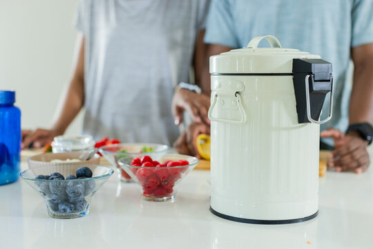 African American couple preparing meal in sunny kitchen, packing berries into white thermos