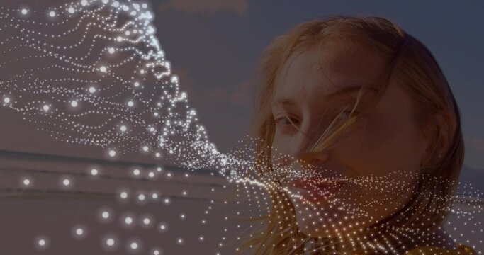 Facing adult woman letting breeze move hair at sandy beach, with white dotted mesh, copy space
