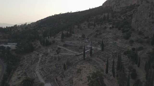 Aerial drone forward shot approaching the Temple of Apollo ruins in Delphi, Greece at sunset.
