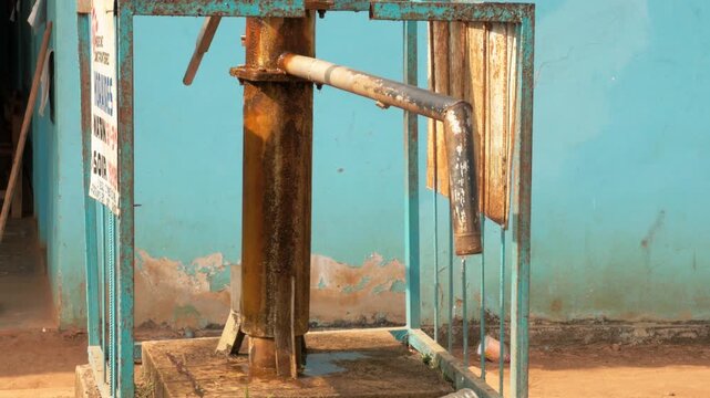 Old manual water pump for water supply in a rural hospital courtyard in Cameroon. Static shot.