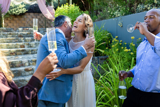 Guests raising flutes and cheering couple for wedding, couple embracing, animated bubbles rising