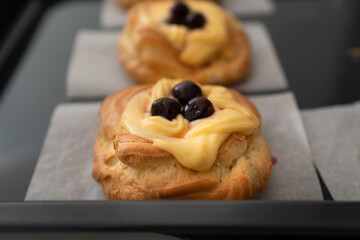 High-angle shot of traditional Italian Zeppole di San Giuseppe, handmade and fresh from the oven. The pastries are resting on a rustic black baking sheet lined with parchment paper, showcasing the gol © Ne_Cloud