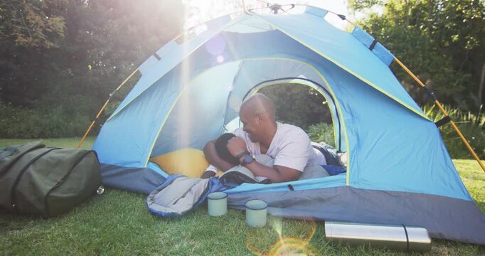 African American father and son, sunlight waking child, sharing play on yellow pillow in blue tent