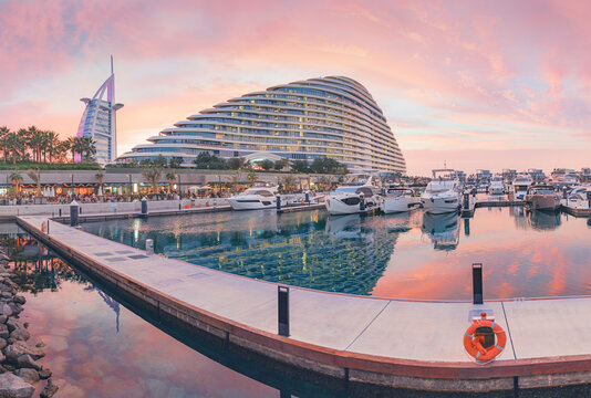 10 January 2026, Dubai, UAE: marina with modern yachts, waterfront restaurants and iconic hotels at colorful sunset, showcasing luxury travel and architecture