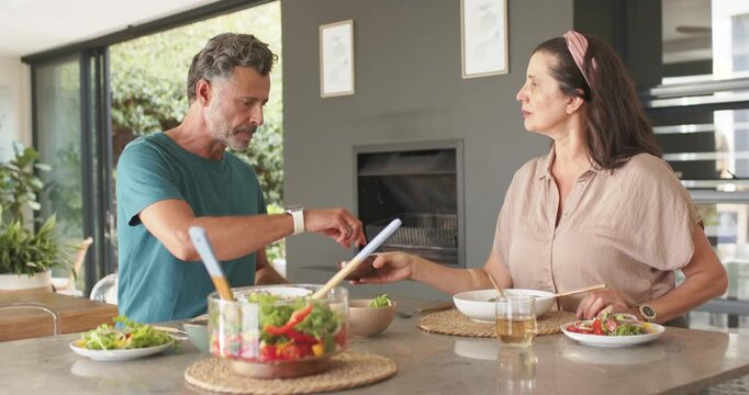 Woman sliding dark bowl starting dressing exchange, man tossing salad and serving plates for meal