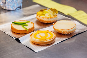 Assembling delicious burgers with toasted buns, sliced peppers, pickles, and mustard at a fast food station