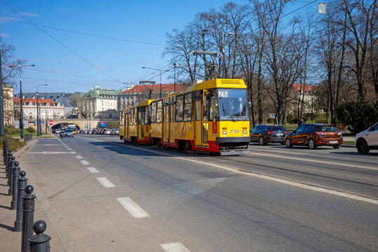 Warsaw, Poland - April 01 2026: A classic yellow Konstal 105Na tram number 1322 travels along Solidarity Avenue against a backdrop of historic architecture.
