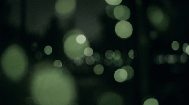 Dark green bokeh background with soft circular light orbs in varying sizes creating dreamy out-of-focus forest night atmosphere
