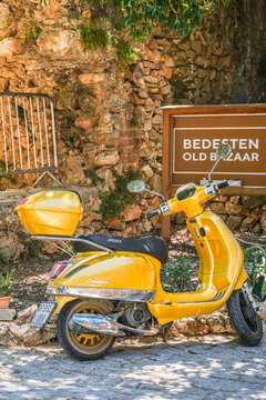 Yellow motor scooter parked near Bedesten old bazaar sign. Classic sunny day vehicle in urban setting. Transport for travel.