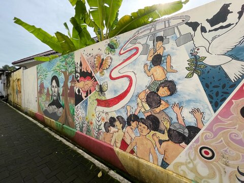 a wall full of artistic murals on a village street in the city of Semarang