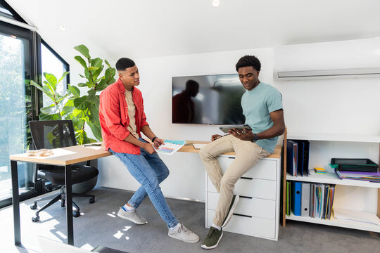 Collaborating Diverse male coworkers reviewing designs in office, with tablet and color swatches