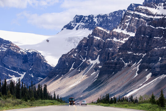 Distant views of Cars and a bus driving on Icefields Parkway with a mountain backdrop, Alberta, Canada