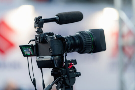 Video camera equipped with an external microphone on a tripod. Integrated audio capture and stable mounting support high quality event recording and media production.