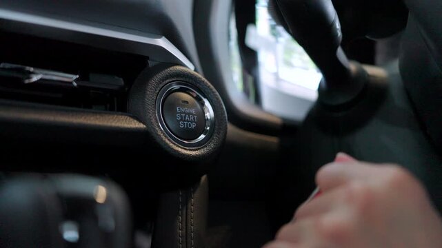 Modern automotive technology. A finger pushes the keyless start-stop button of a new vehicle.
