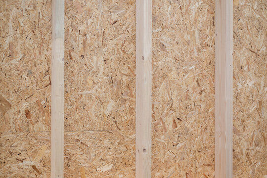 Unfinished wooden wall with vertical studs and oriented strand board panels in construction