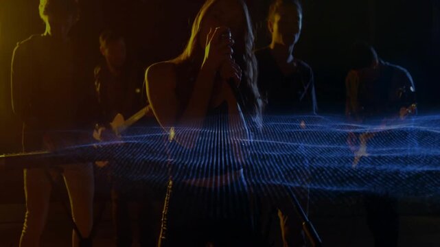 Female lead vocalist stepping, starting music waveform sweeping midline over band, singing into mic
