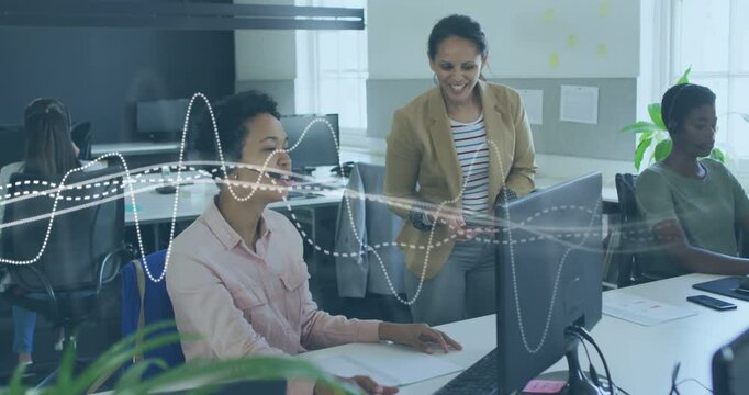 Walking colleague tan-blazer with phone, headset user pointing at monitor typing reviewing waveform
