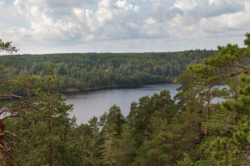 Obraz premium Panoramic view of a boreal forest lake from an elevated rocky vantage point in summer.
