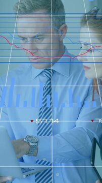 Vertical video: Two analysts reviewing finance at desk man tapping tablet charts cycling to analyze