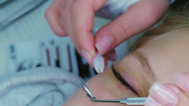 Professional eyelash extension application process with tweezers and brush