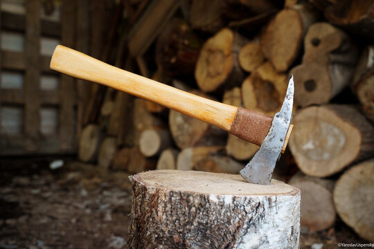 Close-up of a professional fire axe with pick head stuck in a log indoors