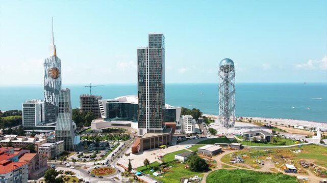 Aerial drone shot shows batumi city during summer day with modern architecture and black sea view.