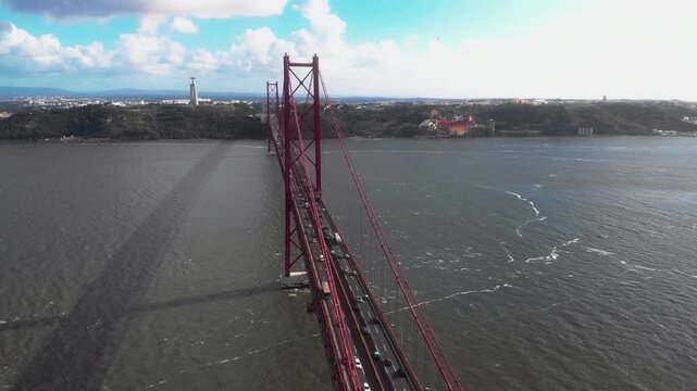 Ponte 25 de Abril bridge with visible traffic over Tagus river and Cristo Rei statue in Lisbon Portugal