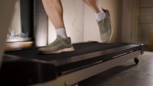 Man standing on treadmill side rails during break in workout. Close-up of a person feet in sneakers resting on the side of a treadmill. Taking a break or finishing a cardio session in a gym
