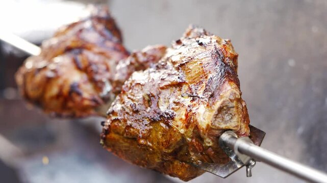 Cooking meat on a spit over an open flame with a focus on grilling techniques and preparation methods