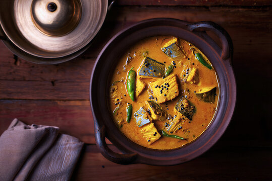 Traditional South Asian Fish Curry Served in a Clay Pot with Fresh Herbs and Spices