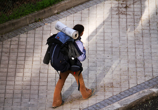 Mujer mochilera con saco, macuto y esterilla enrollada en mochila de viajera de aventura