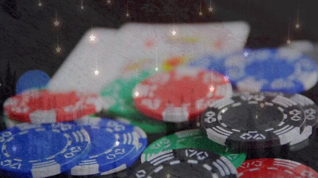 Animation of star icons falling over close up of playing cards and casino poker chips on a table