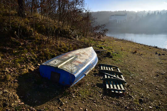 Boat on the bank of the Orlik dam with chateau in the backgroung winter mood