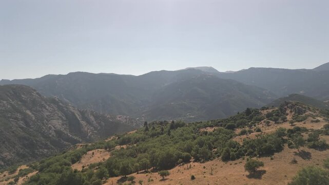Aerial drone forward shot over green countryside landscape in Achaea, Peloponnese, Greece on a sunny day.