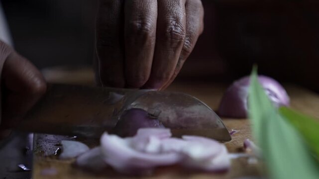 Close-up of onions being sliced during the preparation of a traditional Sri Lankan curry, capturing a key step in cooking.