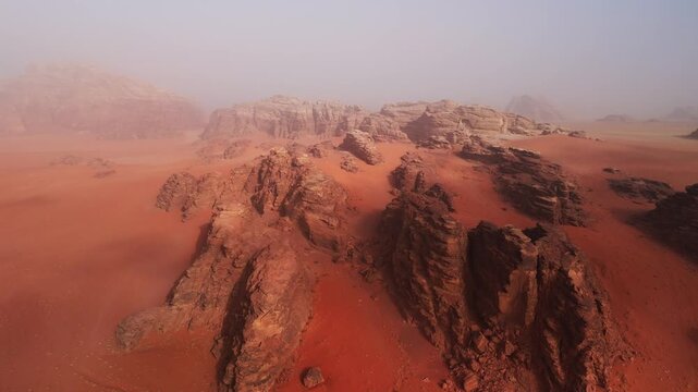 Wide drone over big red rocky mountains in mist in wadi rum desert in jordan