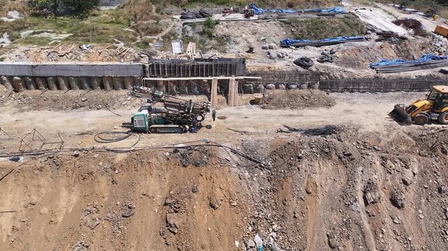 Yellow loader, giant piling rig, Boring Rig Machine and crane preparing foundation at a large construction site. Ground reinforcement and heavy machinery operation in engineering.