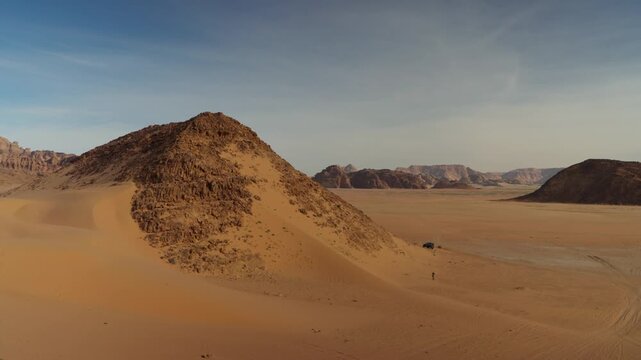 Zoom in on rocky mountain in jordan wadi rum desert with small car
