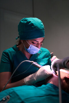 Dentist performing dental procedure on patient in a clinical setting with protective mask and gloves
