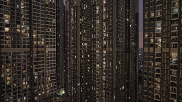 A tight aerial b-roll shot showing the massive scale of residential development in Vietnam. Hundreds of illuminated apartment windows form a modern grid.