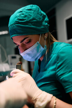 Focused medical professional in surgical scrubs and mask performing a precise dental procedure in clinic