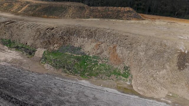 Drone orbit over Panshanger Quarry, Hertfordshire, UK. Low right-hand circle reveals terraced excavation slopes, gravel tracks, exposed earth banks and sparse greenery in daylight.