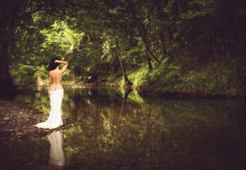 Fototapeta premium tropical rainforest creek scenes featuring an elegant woman with curly hair in a white dress , together with serene reflective landscapes surrounded by lush green forest and soft natural light.