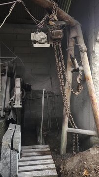 Inside a heavily dust-coated stone cutting workshop, large circular saws and masonry machinery sit idle. The thick layer of silica dust covering the equipment and floor