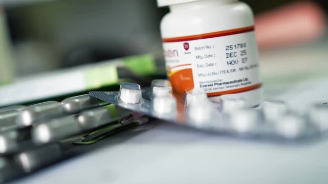 Close-up of blister-packed tablets and a prescription pill bottle on a desk, shallow depth of field, healthcare and medication concept.