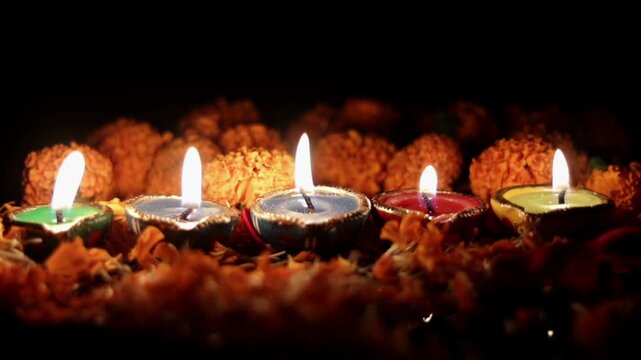 Diwali or Deepavali Festival Diyas or Candles in Line with Marigold and Rose Flower Petals Isolated on Black Background with Copy Space and Selective Focus on the flame, Happy Diwali or Deepavali fest