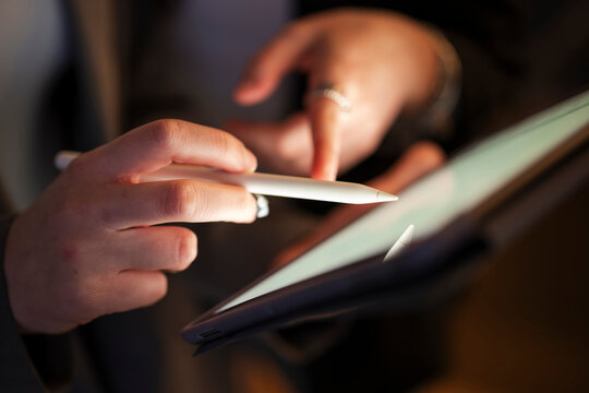 A person's hands use a stylus to interact with a digital tablet, showcasing modern technology and creative work.