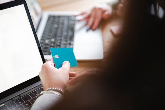 A person uses a credit card to make an online purchase on a laptop, browsing for electronics and home goods.