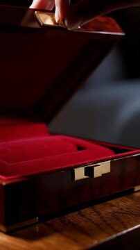 Close-up of Hands Opening a Wooden Jewelry Box Lined with Red Velvet.