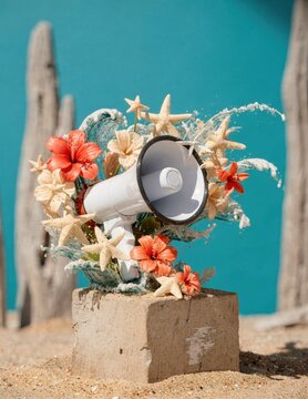 White Megaphone with Tropical Flowers and Starfish on a Sand Pedestal for Beach Event Advertising and Summer Party Marketing with Turquoise Background and Copy Space